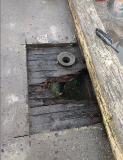 Pavement surface cut open with rotting wooden decking seen below