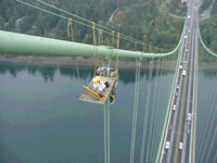 Workmen adjust bolts on a suspender cable band, nearly 300 feet above traffic WSDOT, 10-12-00, MVC-001S