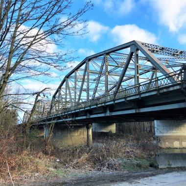 Photo of the Stillaguamish River bridge with a partly cloudy blue sky in the background.