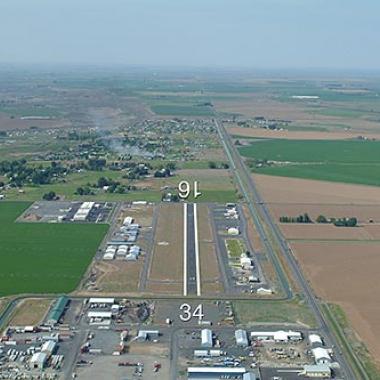 The runway at Moses Lake Municipal airport next to a field of green. 