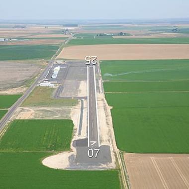 Runway at Othello Municipal airport next to some green fields. 