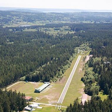 The runway at Whidbey Airpark surrounded by trees and greenery. 