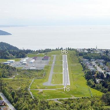 Anacortes Airport Runway located in flat grasslands with a body of water on the edge.
