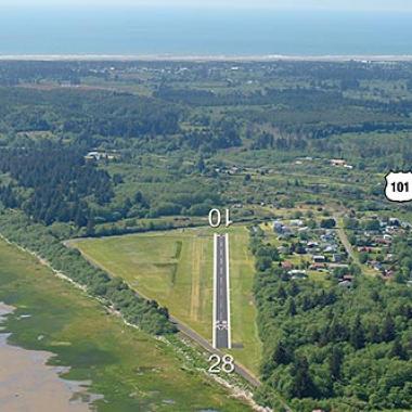 Ilwaco Airport runway located near flat grasslands and forests.