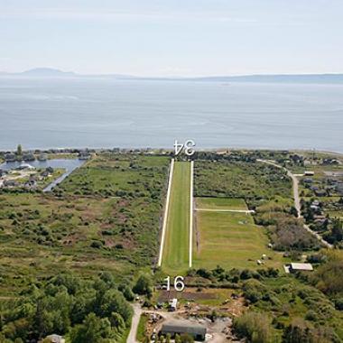 Point Roberts Runway located near trees, grass and a body of water.