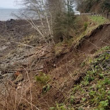 A washed out river bank in between a highway and the Strait of Juan de Fuca