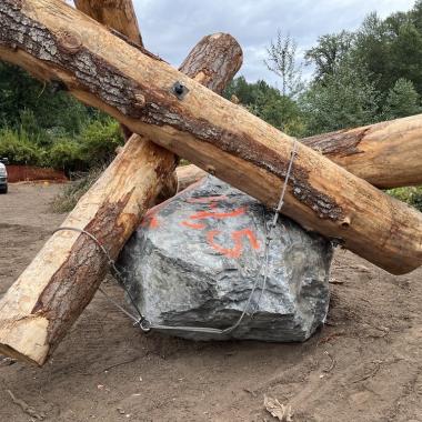 Four large logs and a boulder are tied together to form a log jack.