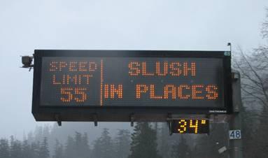 Image of a typical variable message sign on I-90 with speed limit and slush warning message.