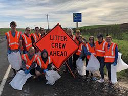 Image of litter removal crew with litter crew ahead sign on road shoulder.