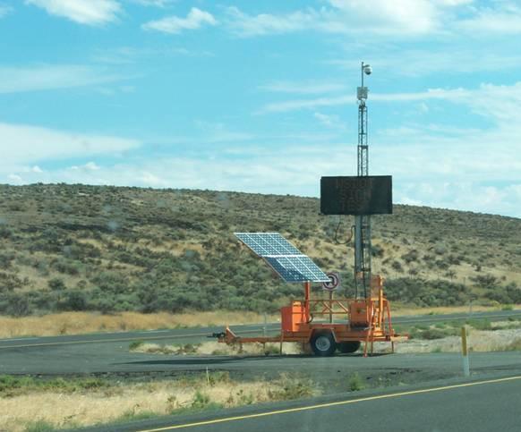 Image of a portable camera and message sign trailer in the median of a multilane divided highway.