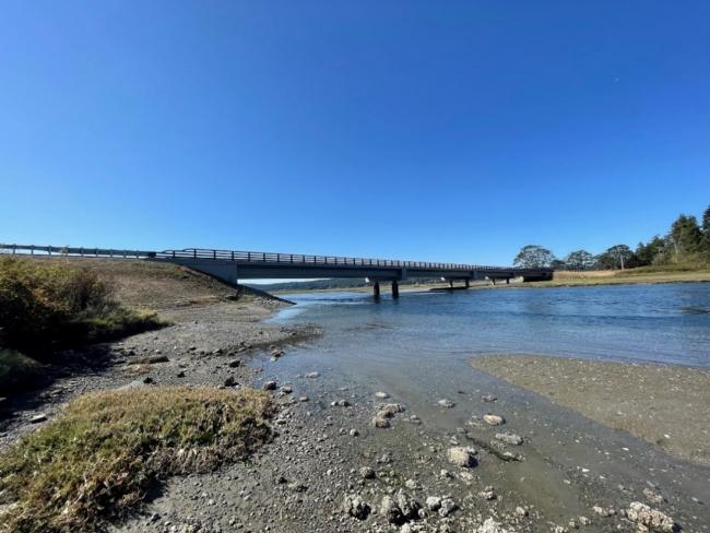 An image of the Kilisut Harbor project area after construction, which shows a tidal channel with a river flowing freely beneath a newly-constructed bridge.