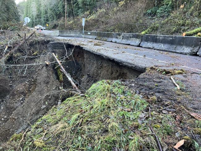 US 101 with a barrier in place showing a washed out road and missing embankment.