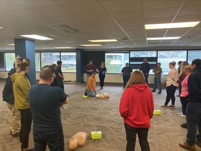 Group of people in a room with first-aid dummies and automated external defibrillators on the ground