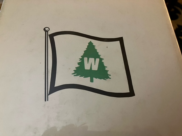 Drawing of a white flag with an green evergreen tree on it and the letter "W" within the tree