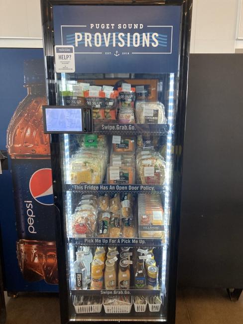 Refrigerated self-serve vending kiosk with various foods and drink inside 