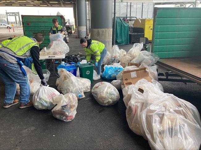 Three people sorting bags of waste