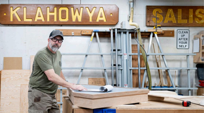 Person standing at a table working in a sign shop