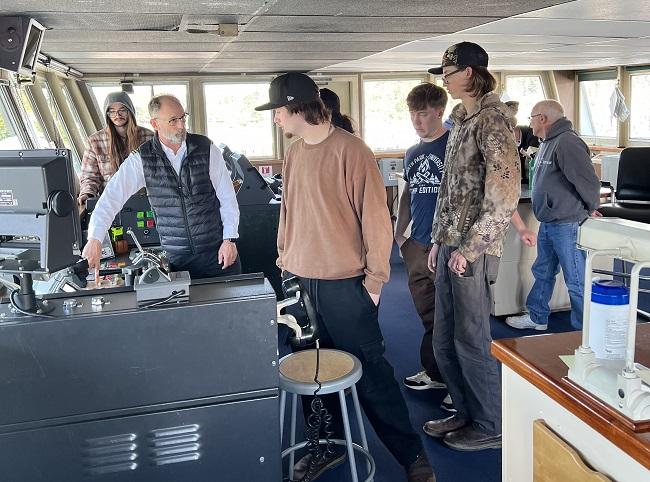 Several people in the wheelhouse of a ferry