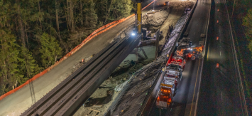 An overhead shot of a nighttime workzone on a roadway through a wooded area.